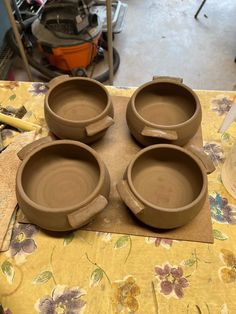 four clay bowls sitting on top of a table