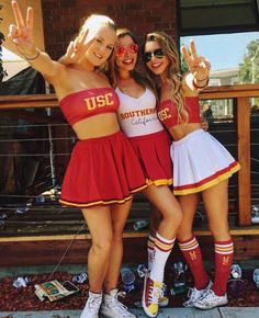 two girls in cheerleader outfits posing for the camera with their hands up and one girl making peace sign