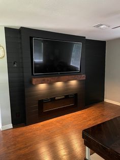 a living room with wood floors and a flat screen tv mounted on the wall