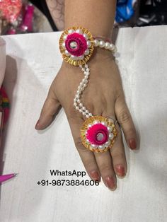 a woman's hand holding two bracelets with flowers on the wrist and pearls attached to it