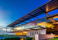 an exterior view of a modern building with glass and steel railings at dusk, overlooking a body of water