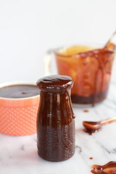 two jars filled with brown liquid sitting on top of a white table next to each other