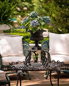 an iron table with flowers on it in the middle of a patio