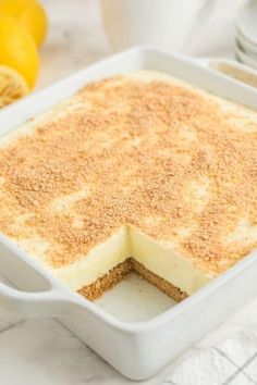 a cake in a white dish on a table with lemons and other food items