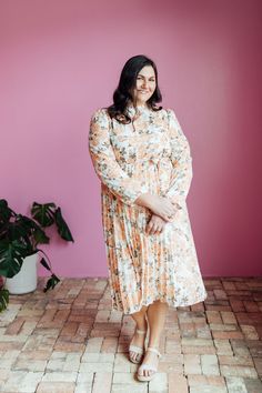 The Oakley Midi dress in a cream base with a peach and brown rose floral design is both stylish and functional. With a high neck, zipper in the back, and long sleeves with elastic cuffs, this dress is comfortable and easy to wear. The elastic waist with a tie creates a flattering silhouette, while the pleated bottom adds a touch of elegance. Model is wearing a small and is 5'8". Plus model is wearing a 2X and is 5'11". Size Chart Length Bust Waist S 47" 34" 32" M 47" 37" 34" L 47.5" 40" 36" XL 47.5" 44" 38" XXL 48" 48" 41" XXXL 48.5" 52" 44" *Measurements are approximate and are measured while hanging* Fabric and Care 100% Polyester Hand wash cold. Do not bleach. Lay flat to dry. Low iron if needed or dry clean. Cream Long Sleeve Midi Dress With Floral Print, Long Sleeve Cream Midi Dress With Floral Print, Long Sleeve Cream Floral Midi Dress, Peach Floral Print Long Sleeve Dresses, Peach Long Sleeve Floral Print Dress, Plus Model, Tiered Dresses, Teen Dress, Cream Base