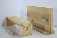 a wooden bench sitting on top of a white floor next to a piece of wood