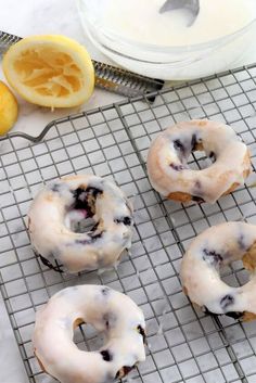 lemon blueberry donuts on a cooling rack next to sliced lemons and a bowl of yogurt