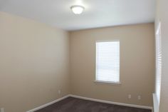 an empty room with no furniture in it and a window on the far wall,