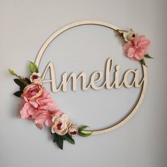 the word amelie is surrounded by pink flowers and greenery in a circular frame on a wall