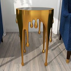 a table with gold paint on it in the middle of a room next to a blue chair