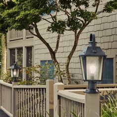 a street light sitting on the side of a wooden fence next to a tree and building