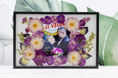 a photo frame with flowers and the words las vegas on it in front of a plant