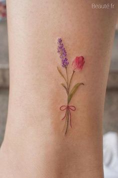 a small tattoo with flowers on the side of her leg, and a ribbon around it