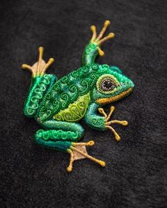 a green and yellow frog sitting on top of a black surface