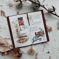 an open book sitting on top of a table next to cotton floss and flowers