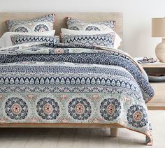 a bed with blue and white bedspread in a bedroom next to a lamp