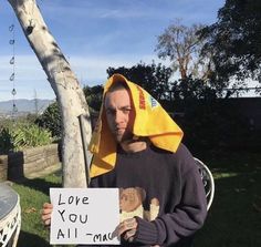 a man sitting in a chair holding a sign that says i love you all time