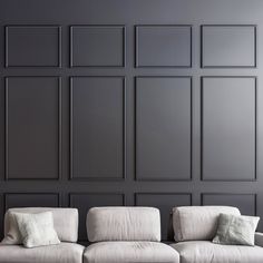 a white couch sitting in front of a wall with black paneling on the walls