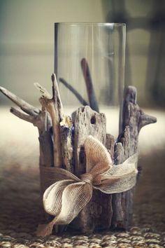 a glass vase filled with driftwood and a bow