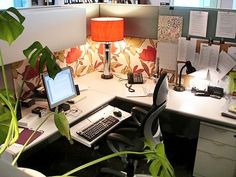 an office cubicle with desk, computer and lamp