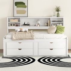 a white bed with drawers underneath it and a rug on the floor next to it