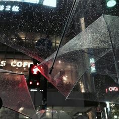 umbrellas hanging from the ceiling in a city at night with rain falling on them