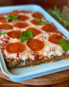 a square pizza sitting on top of a blue tray covered in cheese and pepperoni