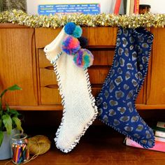 two knitted stockings hanging from a wooden cabinet next to some books and other items