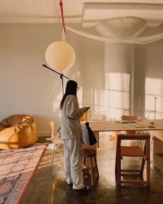 a woman standing next to a wooden table and chair in a room filled with furniture