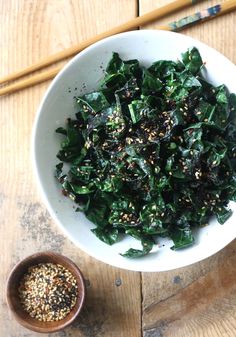 a white bowl filled with greens and sesame seeds