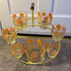 a set of glasses with orange flowers on them sitting on the floor in front of a door