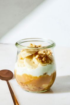 a glass jar filled with dessert sitting on top of a table next to a spoon