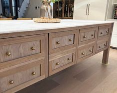 a kitchen island with lots of drawers on it's sides and a vase filled with flowers