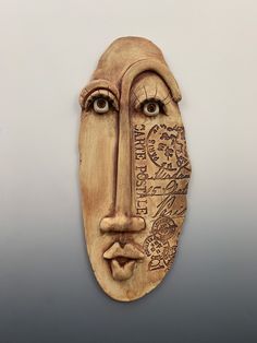 a wooden mask with writing on it's face is shown in front of a gray background