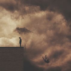 a man standing on top of a building next to a bird flying in the sky