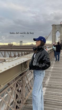 a woman standing on a bridge with her arms crossed and looking off into the distance