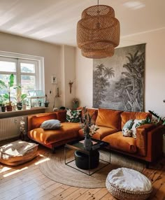 a living room filled with furniture and a large painting on the wall above it's windows