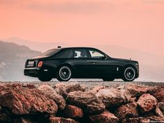 a black car is parked on some rocks