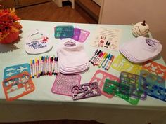 the table has many items on it including hats, markers, and crayons