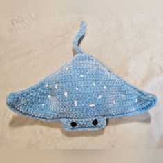 a crocheted blue hat with white speckles on the side and black eyes