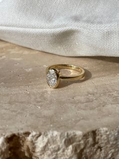 a yellow gold ring with a single diamond in the center sits on a stone surface