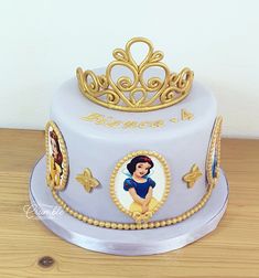 the cake is decorated with an image of snow white and features gold trimmings