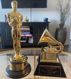 an oscar statue sits on top of a glass table in front of a flat screen tv