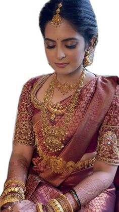 a woman in a red and gold sari sitting down with her hands on her knees