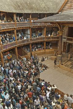 a crowd of people standing around a building with a man on stage in front of an audience