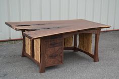 a wooden desk with two drawers on it's sides, sitting in front of a building