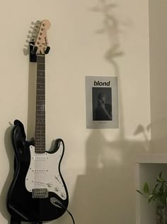 an electric guitar sitting on top of a table next to a plant and a book