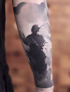 a man's arm with a black and white tattoo design on the left forearm