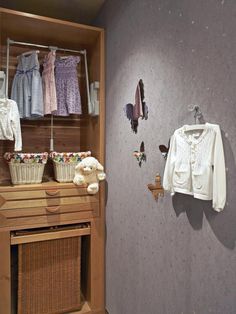 a closet with clothes hanging on the wall and stuffed animals in baskets next to it