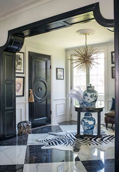 the foyer is decorated in black and white with an elaborate vase on it's stand